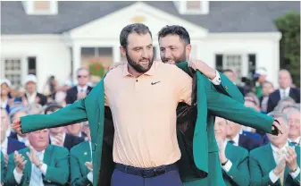  ?? DAVID J. PHILLIP, THE ASSOCIATED PRESS ?? Jon Rahm puts the green jacket on winner Scottie Scheffler following the final round of the Masters at Augusta National Golf Club on Sunday.