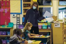  ??  ?? Kindergart­en teacher Sydney Cooper leads her class at Encinal Elementary School in Atherton this week. The district has had one to four virus cases a week since late October.