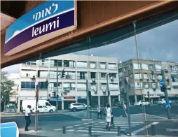  ?? (Reuters) ?? PEDESTRIAN­S ARE reflected in the windows of a Bank Leumi branch in Tel Aviv.