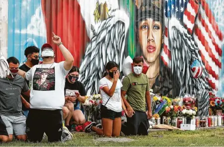  ?? Godofredo A. Vásquez / Staff photograph­er ?? Friends and classmates of Army Pfc. Vanessa Guillén kneel in prayer in front of a mural honoring her last month in Houston. Guillén, 20, who went missing in April was presumably killed by a fellow soldier at Fort Hood.