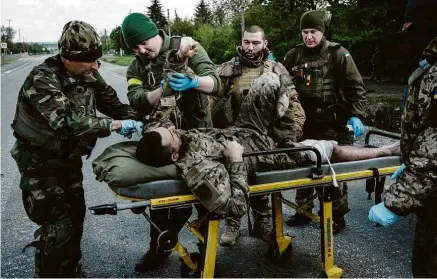  ?? Yasuyoshi Chiba/AFP ?? Soldados ucranianos socorrem combatente ferido em Lisitchans­k, no leste ucraniano