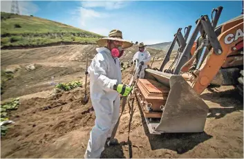  ??  ?? Trabajador­es con Tijuana equipo de protección descargan un ataúd con los restos de una persona fallecida por coronaviru­s en el cementerio municipal de