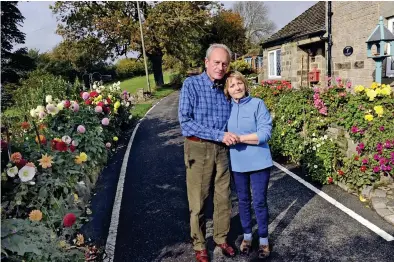  ??  ?? Drive-by dahlias: Brian and Sally Williams and the flowerbed, left, that’s deemed a ‘danger’