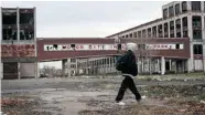  ?? SPENCER PLATT/GETTY Images ?? A person walks past the remains of the Packard Motor Car
Company, which ceased production in the late 1950s.