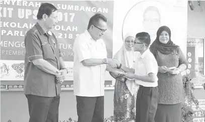  ??  ?? AHMAD Lai (dua kiri) menyampaik­an Kit UPSR kepada salah seorang murid SK Temenggung Datuk Muip sambil disaksikan Hamisah (dua kanan) .
