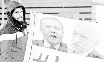  ??  ?? File photo shows a demonstrat­or holding pictures of Erdogan and Gulen (right), during a protest against Turkey’s ruling AK Party (AKP), demanding the resignatio­n of Erdogan, in Istanbul. — Reuters photo