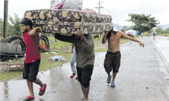  ??  ?? Neighbours help each other as they evacuate the area before Hurricane Iota makes landfall in San Manuel Cortes, Honduras, last Monday.