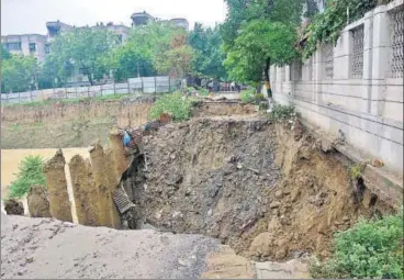  ?? SAKIB ALI /HT PHOTO ?? The boundary walls of some societies were seen practicall­y hanging over the crater at Vasundhara’s Sector 4C on Thursday.