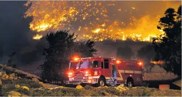  ?? FOTOS AFP ?? Miembros del cuerpo de bomberos llegan al lugar de los hechos para tratar de sofocar el voraz incendio.