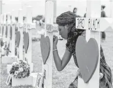  ?? Steve Gonzales / Staff file photo ?? Santa Fe High School student Jai Gillard writes messages on each of the 10 crosses representi­ng victims in front of the school.