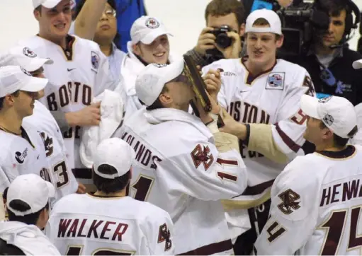  ?? Associated Press ?? Boston College’s Krys Kolanos, center, is surrounded by teammates after the Eagles beat North Dakota, 3-2, in overtime to win the NCAA championsh­ip in 2001. Ty Hennes, now a Penguins assistant, is on the far right.