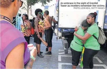  ?? PHOTO: LEON NEAL /GETTY IMAGES ?? An embrace in the sight of Grenfell Tower as revellers remember the victims