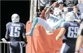  ?? Mark Zaleski / Associated Press ?? Dolphins safety Reshad Jones punctuates his intercepti­on return for a touchdown with a bit of acrobatics against the Titans.