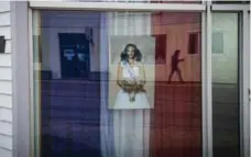  ?? AARON VINCENT ELKAIM/THE NEW YORK TIMES ?? A photo of Alicia Aylies, Miss France, hangs in a St-Pierre window. Proudly self-governing, St-Pierre-Miquelon has a stake in Sunday’s election.