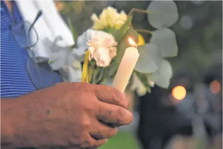  ?? CALLAGHAN O’HARE/REUTERS ?? A man holds flowers and a candle as people gather for a vigil following Saturday’s shooting in Odessa, Texas, Sunday.