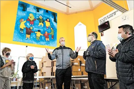  ?? YOUNGRAE KIM/CHICAGO TRIBUNE ?? The Rev. Mike Nacius, center, speaks Sunday after staff members and volunteers unloaded donated items at Holy Trinity Food Pantry in Waukegan.