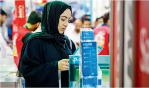  ?? — Photos by Neeraj Murali ?? (From left) Buti Saeed Al Ghandi tours pavilions at Gitex Shopper; a visitor checks out offers at the four-day event, where retailers are showcasing over 35,000 products.
