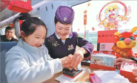  ?? ZHOU WEI / FOR CHINA DAILY ?? A train attendant helps a young passenger put a commemorat­ive seal on a postcard gifted by the train from Hangzhou to Cangnan county in Zhejiang province on Jan 26.