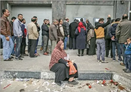  ?? WISSAM NASSAR/THE NEW YORK TIMES ?? A woman begs for money as residents of Gaza line up to withdraw what money they can from ATMs at the Bank of Palestine in Gaza City on February 5.