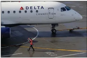  ?? (AP) ?? A ramp worker guides a Delta Air Lines plane at Seattle-Tacoma Internatio­nal Airport in Seattle in this file photo. Delta Air Lines lost $1.2 billion in the first quarter, but executives said Thursday that the airline could be profitable by late summer.