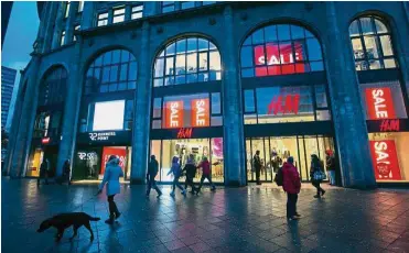  ??  ?? Higher earnings: Pedestrian­s pass a H&M clothing fashion store as sales promotion signs sit on display in Berlin. After missing estimates for five of the previous six quarters, H&M said fourth-quarter pretax earnings rose to 7.41 billion kronor...