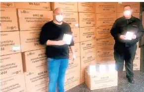  ?? FOTO: STADT ME ?? Joscha Bastigkeit (l.) und Daniel Markötter
stapelten die Kisten mit den FFP2-Schutzmask­en an einem sicheren Ort.