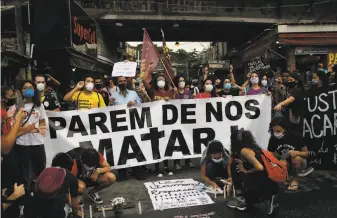  ?? Silvia Izquierdo / Associated Press ?? Activists and the relatives of people shot by officers gather with a banner that reads “stop killing us” to protest the deadly police operation in the Jacarezinh­o favela of Rio de Janeiro.