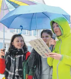 ?? FOTO: GERD MÄGERLE ?? Mit Regenjacke­n und Schirmen haben die Schüler bei der Protestbew­egung am Freitag versucht, trocken zu bleiben. Das gelang aber nur bedingt.