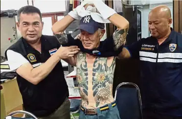  ?? — AFP ?? Body art giveaway: Officers showing Shirai’s gang-style tattoos to reporters at a police station after his arrest in the central Thai province of Lopburi.