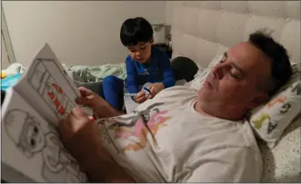  ?? JAE C. HONG/ASSOCIATED PRESS ?? Scott Quinn and his 4-year-old son, Ethan, work on coloring books in a bed in Concord, Calif., Wednesday, Nov. 1, 2023. Ethan’s parents are among those who have opted for a private daycare instead of a free “transition­al kindergart­en.” Quinn said he has been discourage­d to see Ethan — one of the oldest kids in his daycare class — pick up the behavior of kids who are several years younger than him. “In retrospect, it would have been better to send him to school to be around kids his age and older,” he said.