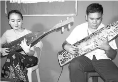  ??  ?? Iyumi Ului (left) with her husband Donny playing the sape at Borneo Evangelica­l Mission Church recently. - Bernama photo