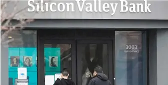  ?? JEFF CHIU/AP ?? People look at signs posted Friday outside Silicon Valley Bank in Santa Clara, California.