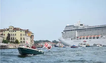  ?? Anadolu Agency/Getty Images ?? Activists in Venice protesting against cruise ships, as the MSC Orchestra left the city from the Giudecca Canal earlier this month. Photograph: