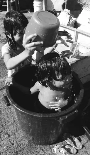  ?? ARNOLD ALMACEN ?? HOT DAY, COOL KIDS Two children in Tondo, Manila, have more fun taking a bath “tabo” style on the hottest day of the year in the metropolis, according to Pagasa.