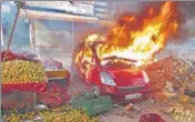  ?? PTI ?? A car in flames near a vandalised fruit shop at Chand Bagh.