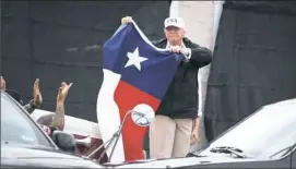  ?? Jim Watson/AFP/Getty Images ?? President Donald Trump holds the state flag of Texas outside the Annaville Fire House after attending a briefing on Hurricane Harvey on Tuesday in Corpus Christi.