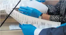  ?? JOE CAVARETTA/SUN SENTINEL ?? Members of the canavassin­g board examine a duplicate ballots Thursday at the Broward Supervisor of Elections office in Lauderhill.