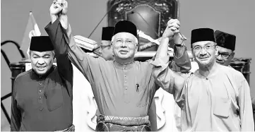 ??  ?? Najib holds up the hands of Ahmad Zahid (left) and Hishammudd­in after a dialogue session during the Umno General Assembly 2017 at the Putra World Trade Centre. — Bernama photo