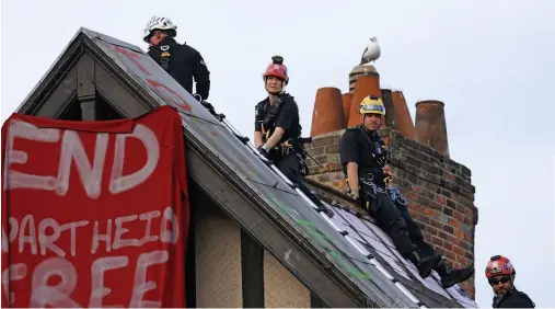  ?? Photograph­s: John Myers ?? Left, police officers - along with a lone seagull - check the rooftop of the squat in central Bristol; below, riot police move in to evict squatters