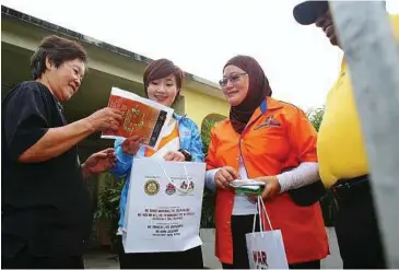  ??  ?? Spreading a message: 1Malaysia KKM Health Ambassador Phoebe Yap (second from left) and Norhayati (second from right) handing out informatio­n pamphlets and Abate packets to Mak Sow Yin, 69, a resident in the area during the gotong-royong programme.