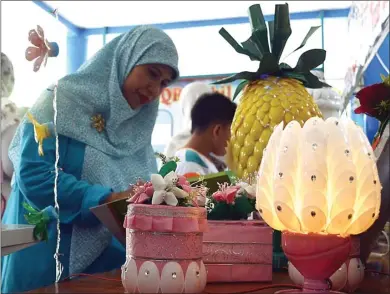  ?? ADI WIJAYA/JAWA POS ?? MACAM-MACAM: Elvi Soraya, juri yang juga guru, sedang menilai karya siswa dari daur ulang sampah.