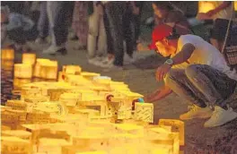  ?? PATRICK CONNOLLY / ORLANDO SENTINEL ?? A man pushes lanterns away from the shore during the Orlando Water Lantern Festival at Orlando Watersport­s Complex on March 16, 2019.