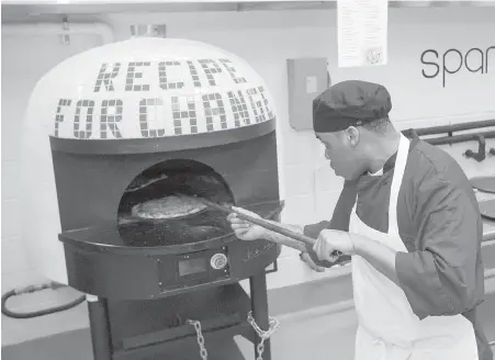  ?? ASSOCIATED PRESS PHOTOS ?? Inmate Marcus Clay pulls pizza from an oven at the Cook County Jail in Chicago. Medium-security inmates are allowed to order pizzas made by participan­ts in the Recipe for Change program.