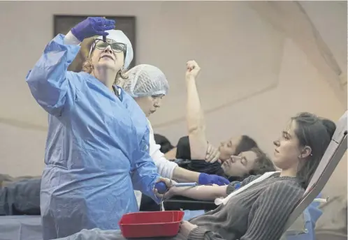  ?? ?? Young people donate blood for wounded Ukrainian personnel during a session held in a church basement in Kyiv