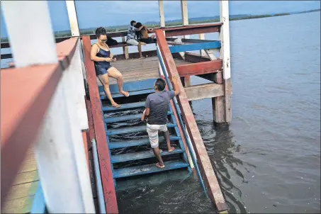  ?? [JABIN BOTSFORD/THE WASHINGTON POST PHOTOS] ?? People take photos in an area that used to be a beach along the Xingu River, before it was flooded by the dam.