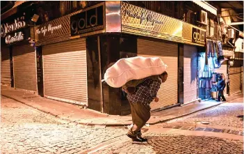  ?? — AFP photo ?? A porter carries belongings on a street early morning near Grand bazaar in Istanbul.