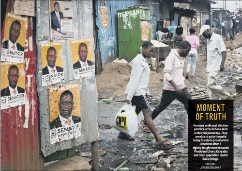  ??  ?? Kenyans walk past election posters in the Kibera slum in Nairobi yesterday. They are due to go to the polls today to vote in presidenti­al elections after a tightly-fought race between President Uhuru Kenyatta and main opposition leader Raila Odinga.