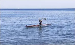  ?? The Maui News / LILA FUJIMOTO photos ?? Kihei Canoe Club member Bonney Esbensen raises her paddle as she nears shore after completing the Paddle for Hunger course off Kihei on Thursday morning.