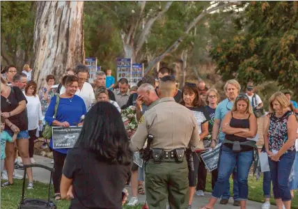  ?? Cory Rubin/The Signal ?? (Above) Capt. Robert Lewis of the Santa Clarita Valley Sheriff’s Station addresses an emotional crowd at the Evening of Remembranc­e event at Central Park on Wednesday. (Below) Two California Highway Patrol officers walk alongside hundreds in attendance.