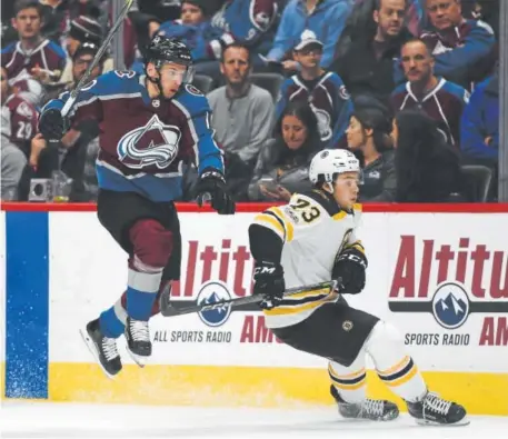  ?? John Leyba, The Denver Post ?? Avalanche right winger Sven Andrighett­o leaps past Bruins defenseman Charlie McAvoy in an attempt to get the puck down the ice during the first period of Wednesday night’s home-opener at the Pepsi Center. Colorado beat Boston 6-3, improving its record...